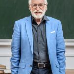 smiling-grey-hair-professor-standing-in-lecture-ro-DNUL3FY.jpg